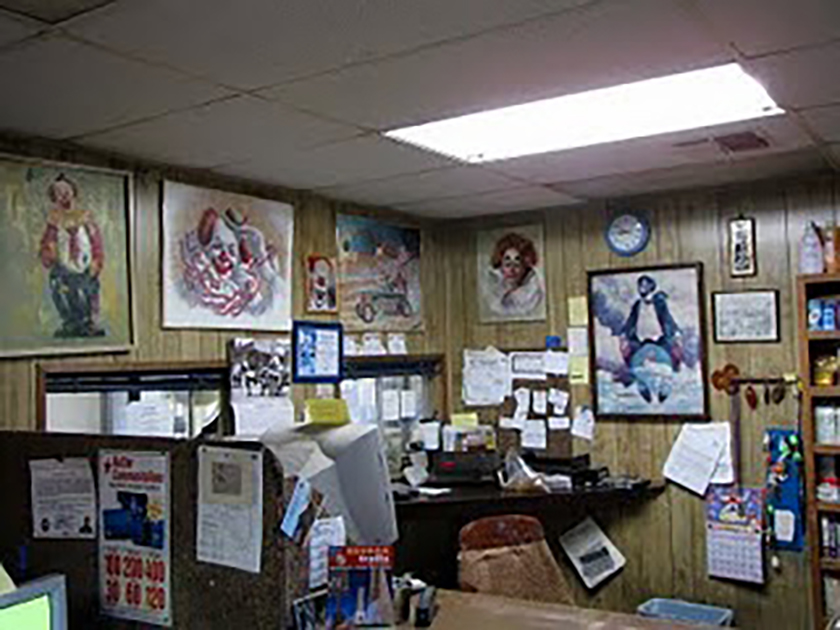 Interior of the office for a clown-themed motel, with many framed images of clowns on the wooden walls