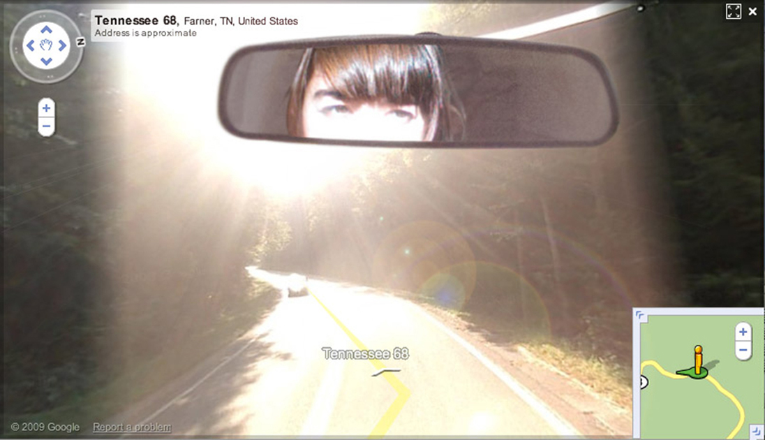 Jenny Odell's face in her rearview mirror, squinting at light, photoshopped in front of Street View of a road in Tennessee where the sun is coming directly at the camera
