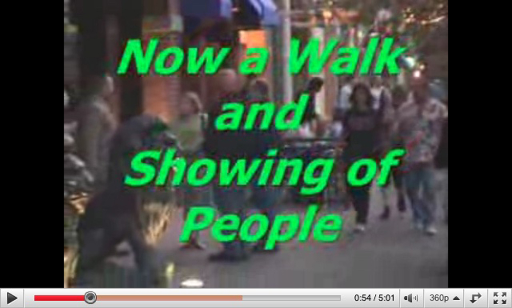 Screen shot from a Youtube video of people walking in Denver, overlaid with bright green text that says, Now a Walk and Showing of People